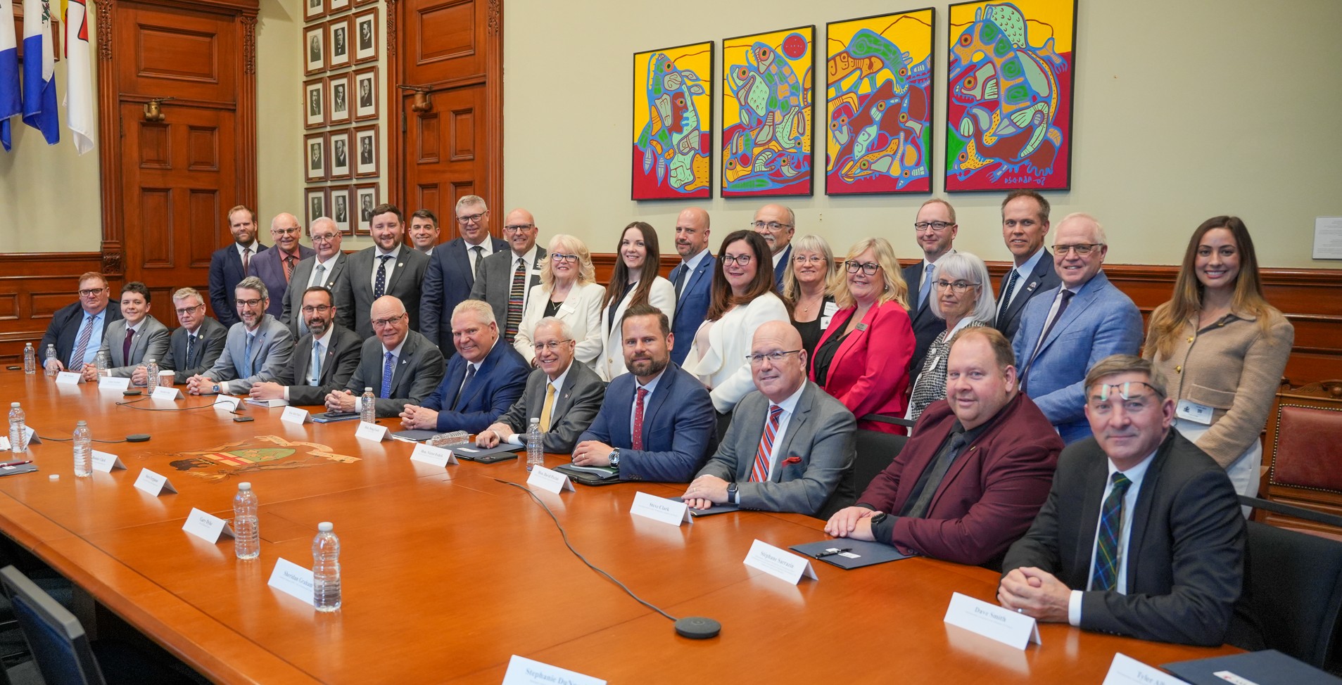 group of people, some sitting and some standing behind a long boardroom table