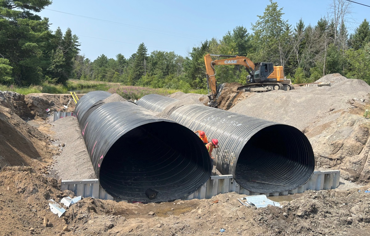 two large culvert pipes in an active construction site, piece of equipment in the background