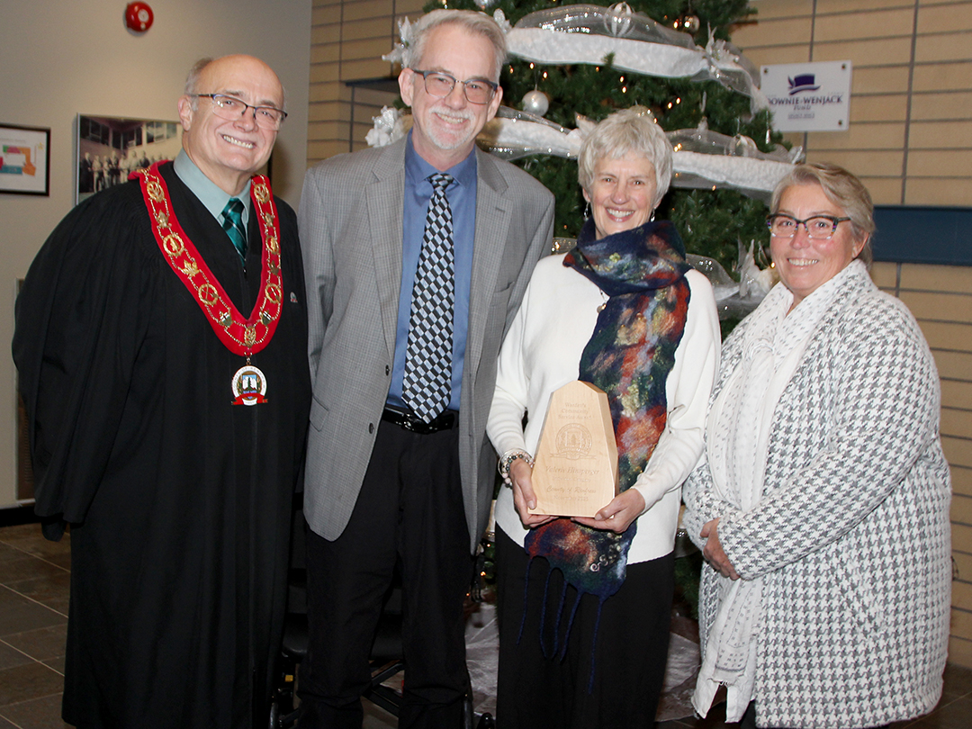 group of five people in front of a Christmas tree