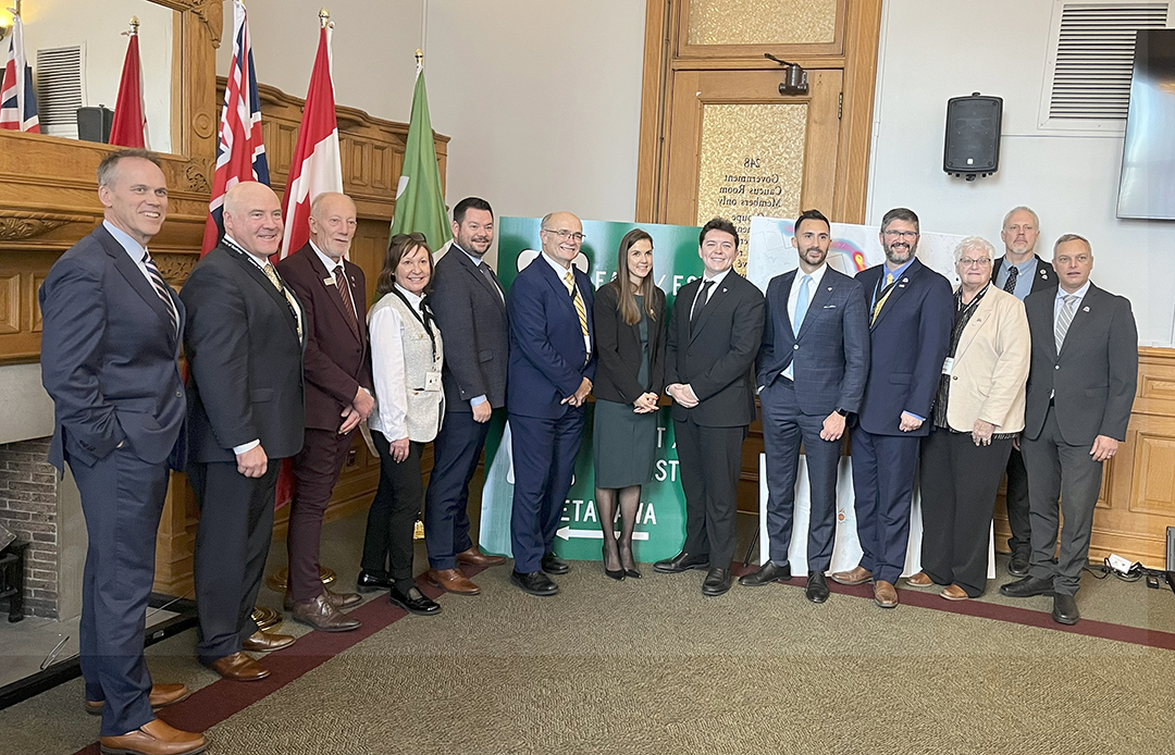 group of people standing in front of flags and a Highway 17 sign