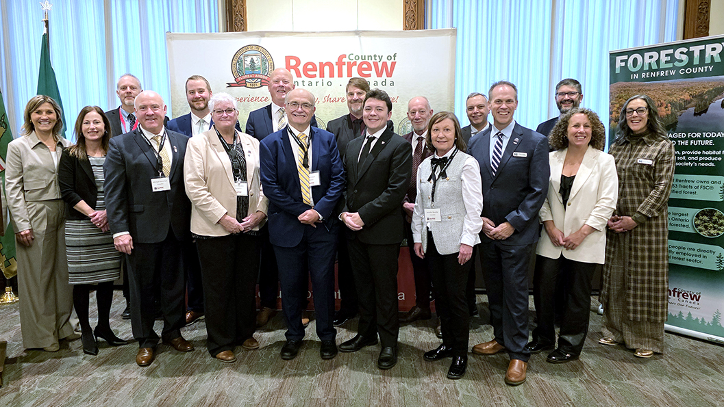 group of people in two rows standing in front of a County of Renfrew backdrop with Forestry banner on the right