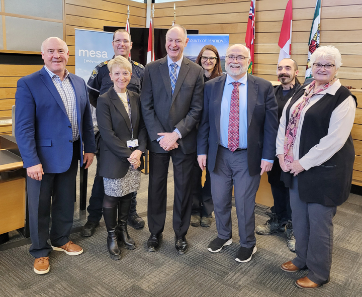 Group standing in front of banners and flags following funding announcement