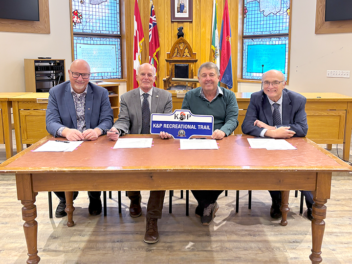 signing ceremony with four men sitting at a table