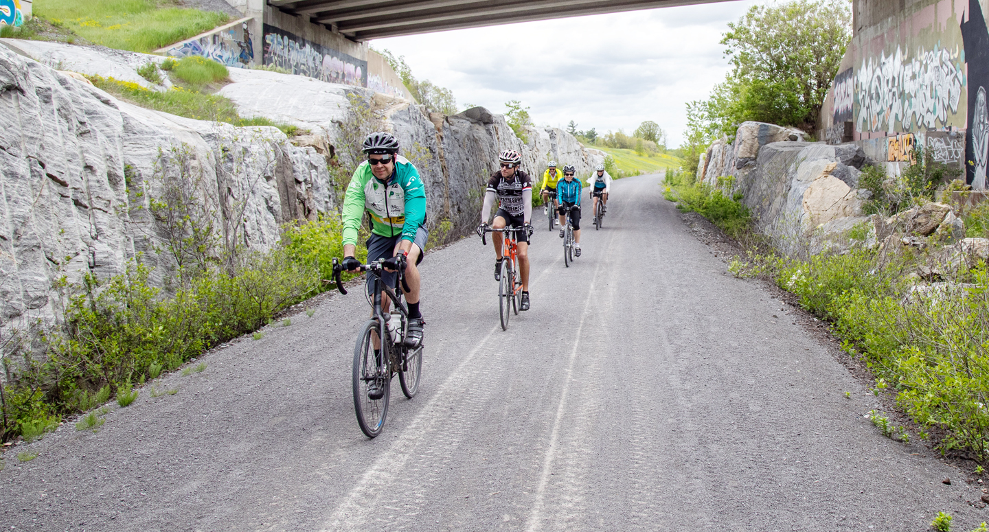 Group of cyclists on a gravel trail with rocks on either side 
