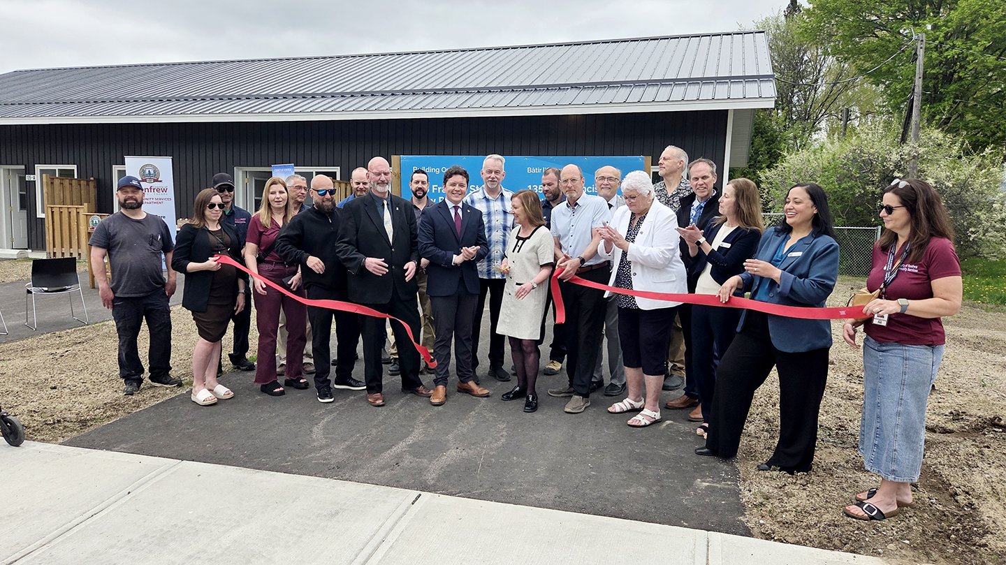group of people cutting a red ribbon to mark the official opening of new triplex in Renfrew