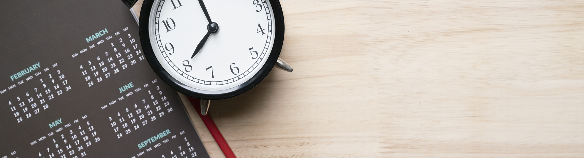 alarm clock, pencil and calendar on the table